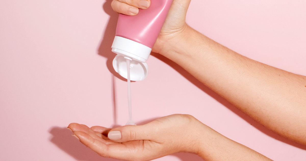 Mulher aplicando creme de pentear em cabelo cacheado, destacando a definição dos cachos após o uso do produto.